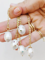 ARIEL GORDON - A collection of Baroque Pearl Drop Necklaces held in a hand.   