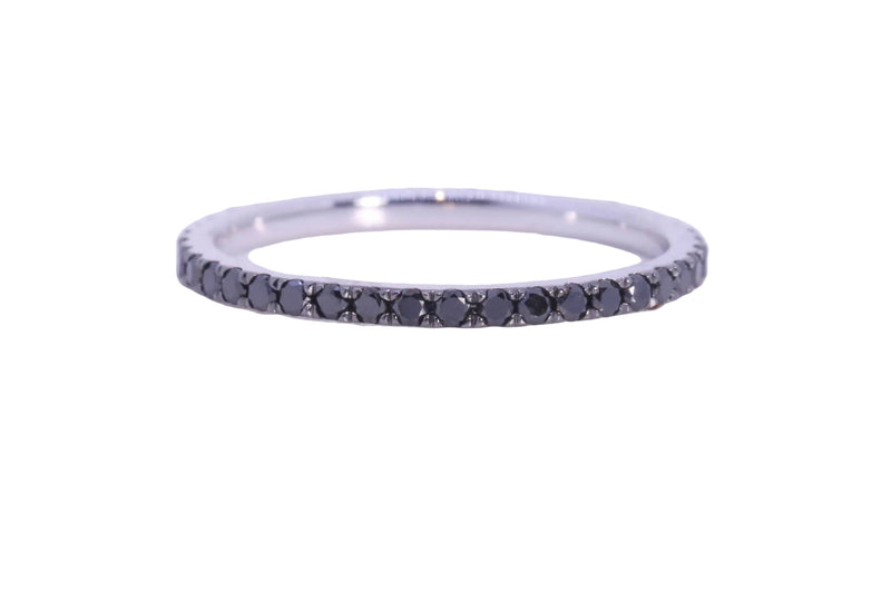 A thin silver eternity ring set with small round black gemstones, photographed on a clean white background.