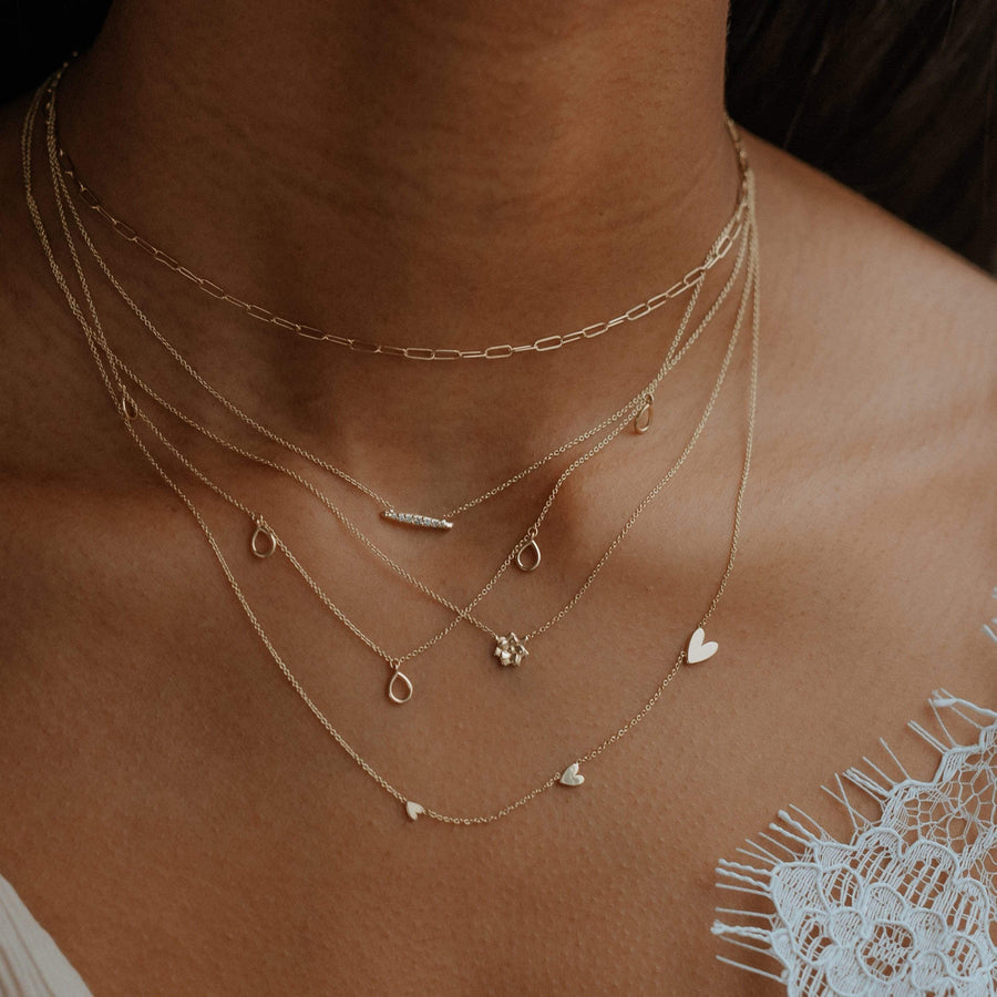 Horizon Necklace in  14k yellow gold with a bar set with 7 diamonds. . Shown in a stack on model with 4 other necklaces.