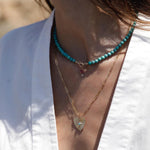 ZAHAVA~ 20 mmTurquoise Sunbeam Heart Charm on a gold chain close up view.