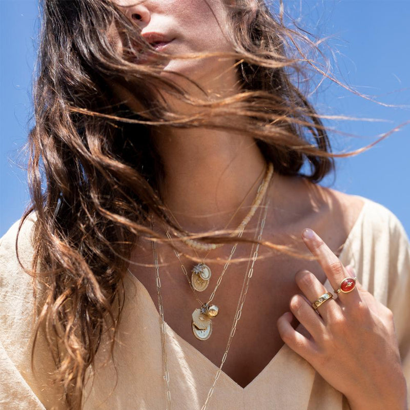 Model wearing a layered complement of ZAHAVA Necklaces including the  Golden Atlas Charm in10 k Yellow Gold 