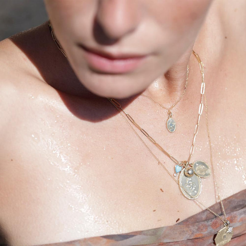 Model wearing a layered complement of ZAHAVA Necklaces including the Mini 8mm Golden Atlas Charm Yellow Gold.