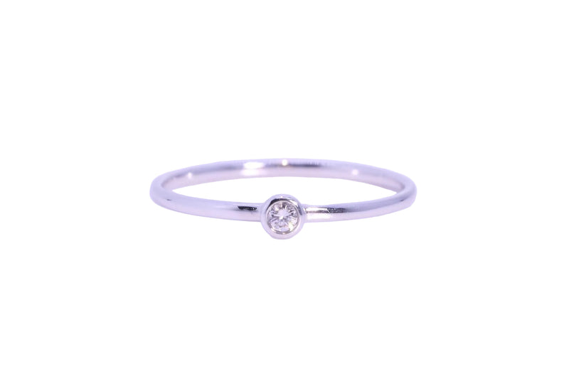 A delicate white gold ring featuring a single round-cut clear gemstone in a bezel setting, centered against a plain white background.