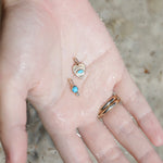 Mini Turquoise Sunbeam Heart Charm in 10 K Yellow Gold laying in the palm of a hand 