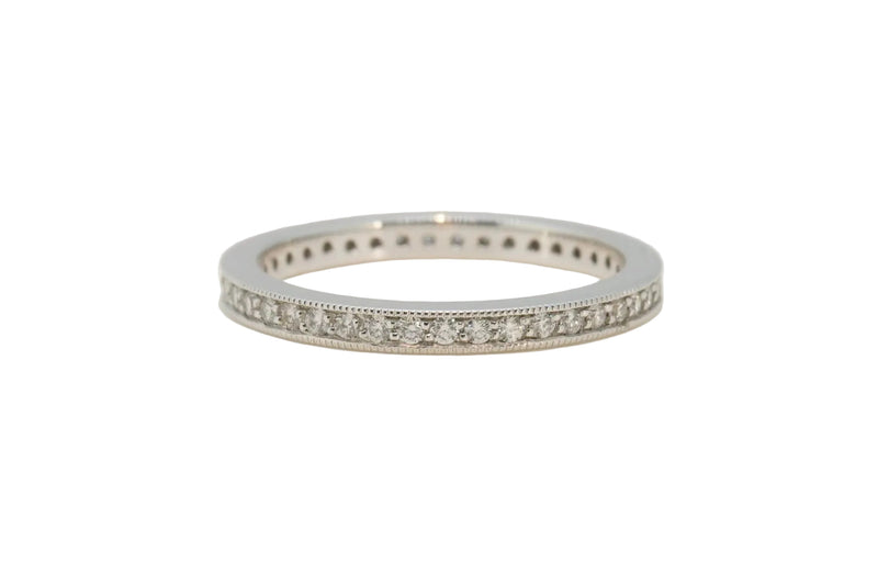 A silver-tone eternity band ring set with small clear round-cut stones, photographed on a plain light gray background.